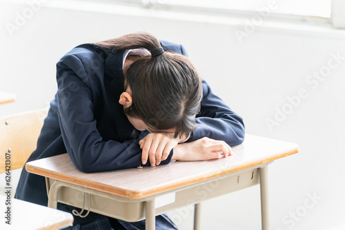 Fototapeta 学校の教室で女子高校生・中学生が俯いて悩んでいる（悩む・困る・ストレス） 