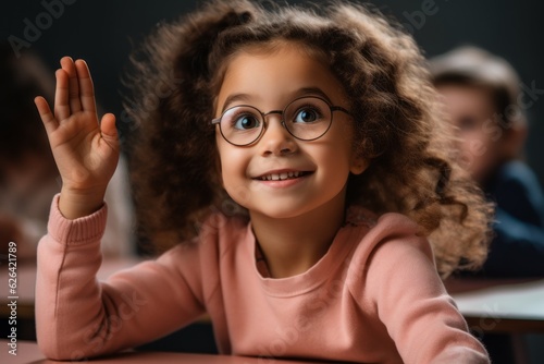 The girl raises her hand for an answer in the classroom. Back To School concept. Backdrop with selective focus © top images