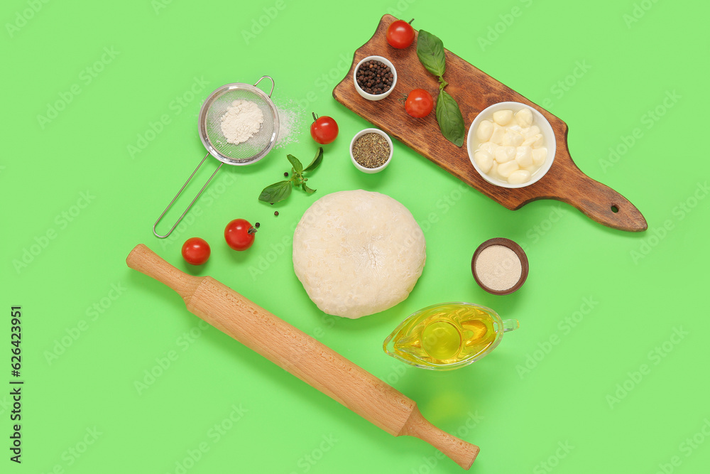 Raw dough and ingredients for preparing pizza on green background Raw dough and ingredients for preparing pizza on green background