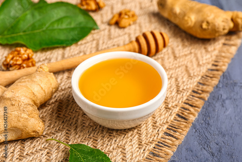 Bowl of sweet honey with walnut and ginger on blue wooden background