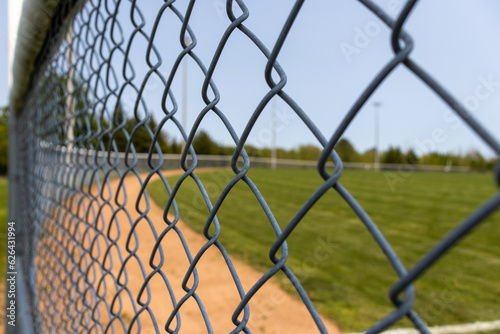 Wire metal fence with baseball field diamond in background. Taken in Toronto, Canada.