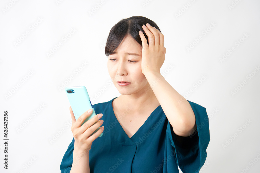 スマートフォンを持って頭を抱える女性　白背景