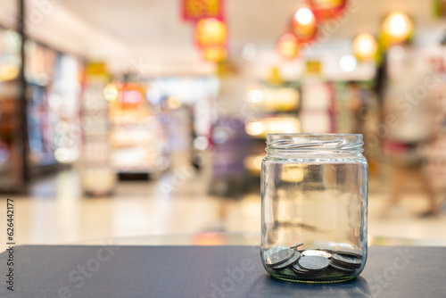 Coins in glass jars on table against blurred background concept of savings