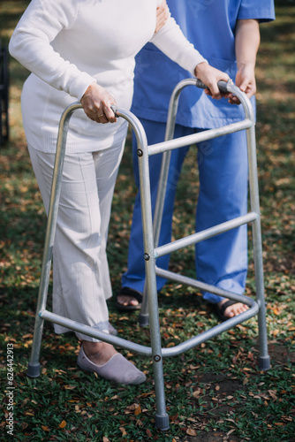 Fototapeta young asian physical therapist working with senior woman on walking with a walke