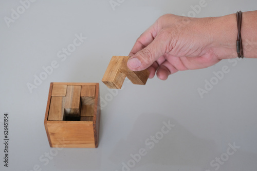 Close up shot of isolated hand playing with wooden cube puzzles photo