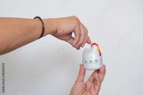 Isolated portrait of pair of hands winding white kitchen timer