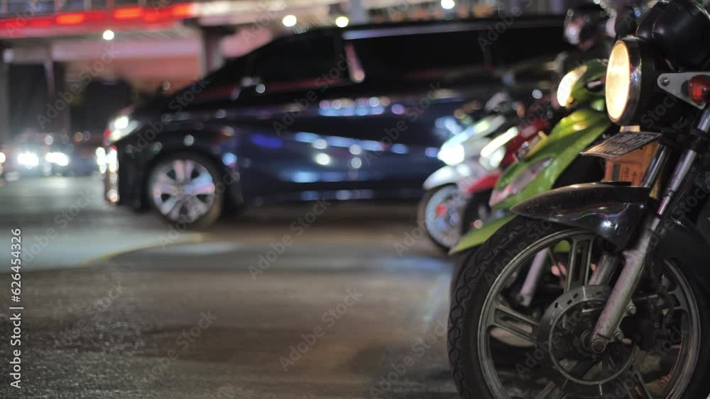 Motorcycles and cars are waiting at a red light under Jakarta's ASEAN pedestrian bridge at night. There are cars and motorcycles passing in front of them. Motorcycles and cars are waiting at a red light under Jakarta's ASEAN pedestrian bridge at night. There are cars and motorcycles passing in front of them.