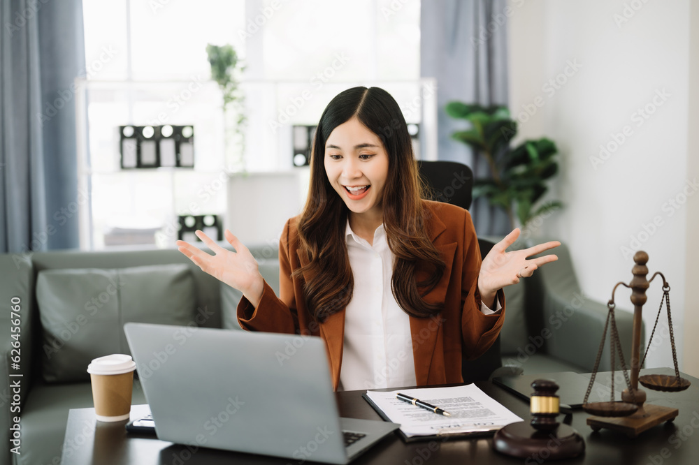 Asian female lawyer chatting online with client on laptop, smartphone discussing details of lawsuit. in modern office Asian female lawyer chatting online with client on laptop, smartphone discussing details of lawsuit. in modern office