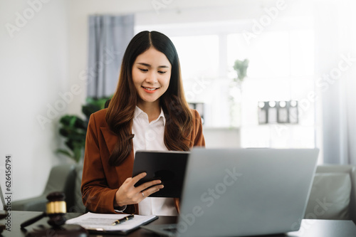 Asian lawyer woman working with a laptop and tablet in law office. Legal and legal service concept. Looking at camera..