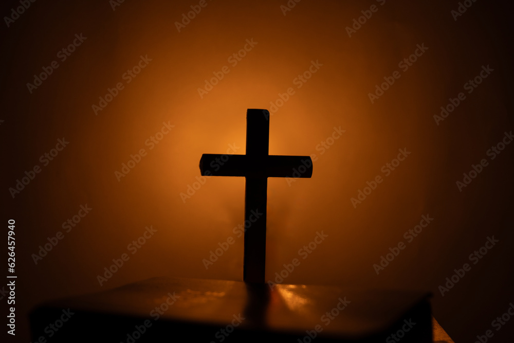 Light candle with holy bible and cross or crucifix on old wooden background in church.Candlelight and open book on vintage wood table christianity study and reading in home.Concept of christ religion