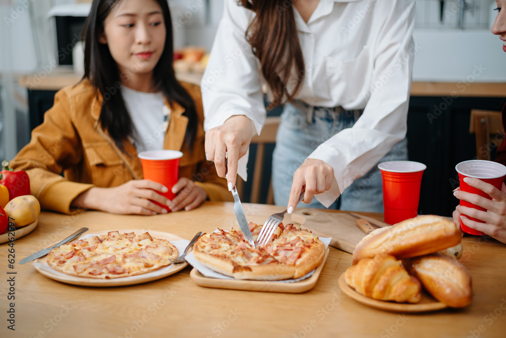 Happy multiracial friends chatting, eating pizza together, having small party at home