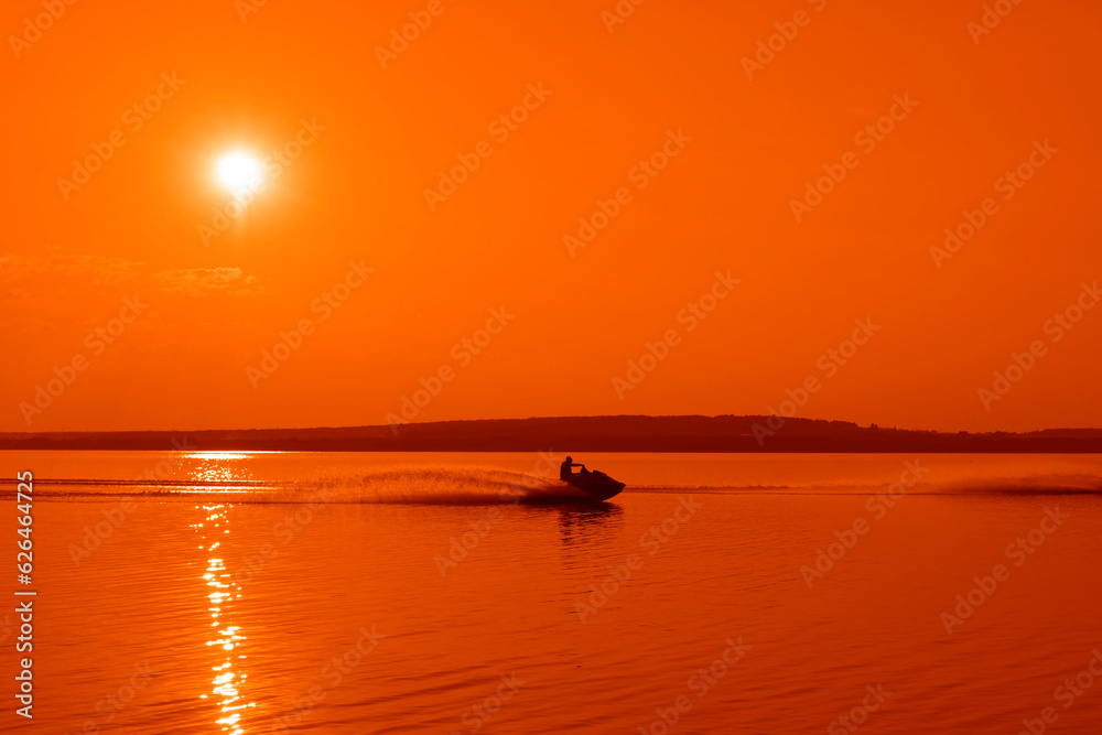 profile view of silhouette man riding a fast water scooter through some shallow waves on a Golden Coast beach on sunset. Silhouette of man riding a water scooter and jumping over a wave on sunrise. profile view of silhouette man riding a fast water scooter through some shallow waves on a Golden Coast beach on sunset. Silhouette of man riding a water scooter and jumping over a wave on sunrise.