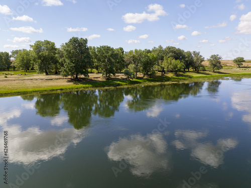 The clouds and trees are mirrored in the water of Irtysh river. Near outpost Talitsa in Kazakhstan.