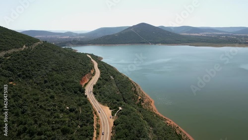 Road that winds through the mountain next to a lake of calm waters in the center of Spain. photo