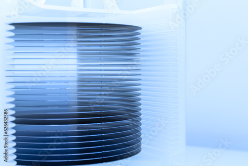 A lot of silicon wafers packed in a plastic storage box in the clean room of a semiconductor foundry ready for microchip production.