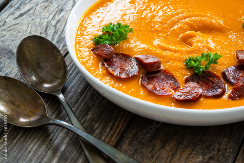 Sweet potatoes cream soup with choriso sausage on wooden background photo