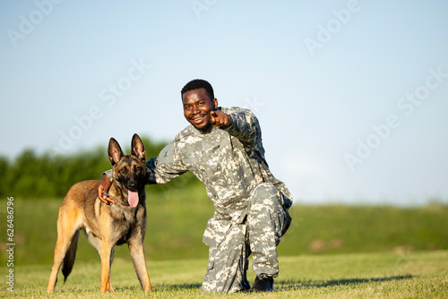 Portrait of smiling soldier and military dog looking to the camera.