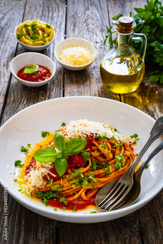 Linguine with tomato sauce, parmesan cheese and basil leaves served on wooden table 