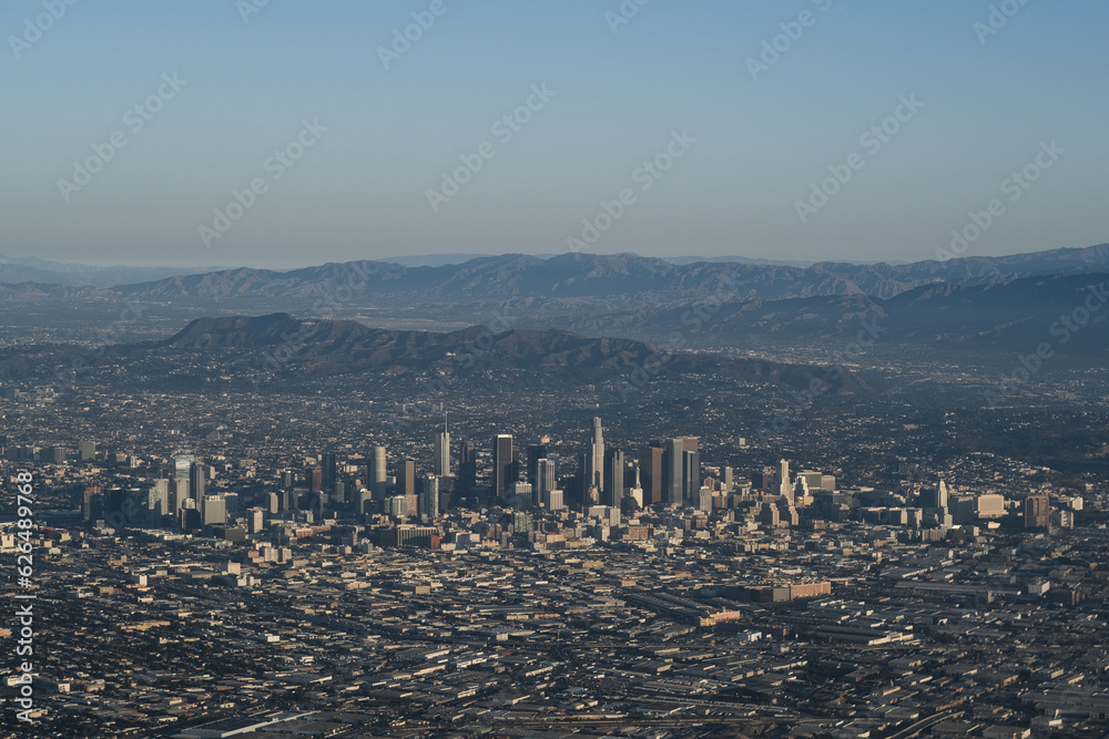 Obraz premium An aerial view of Downtown Los Angeles, showing the LA skyline and the mountains and valleys in the distance.