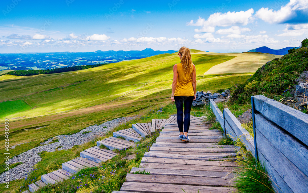 Woman with sport clothes walking on wooden path in mountain- Auvergne in France