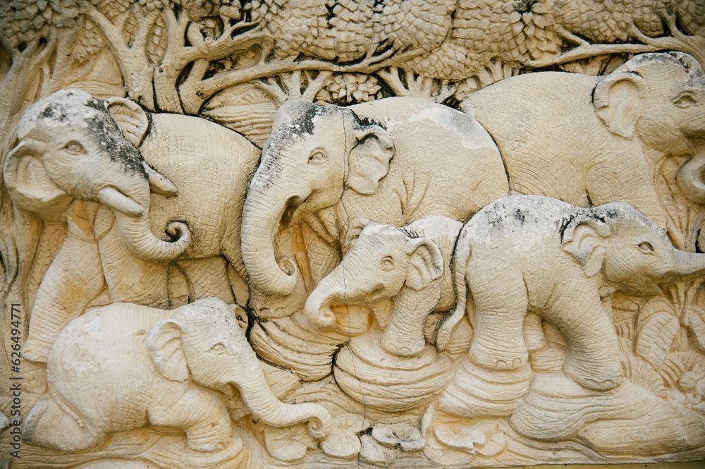 stucco on the facade of the house, half protruding from the wall, the image of a family of elephants