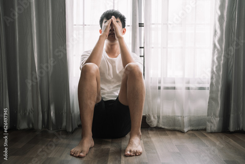 Sad and depressed young male sitting on the floor in the room, sad mood,feel tired, lonely and unhappy concept.