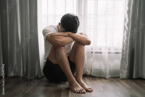 Sad and depressed young male sitting on the floor in the room, sad mood,feel tired, lonely and unhappy concept.