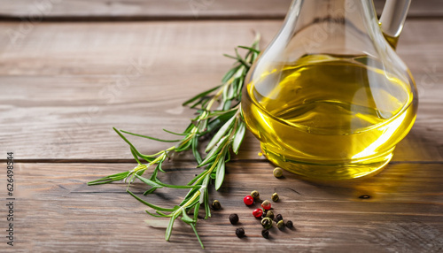 Flavored olive oil with rosemary and pepper on wooden background. Copy space.