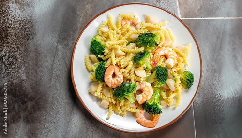 Pasta with broccoli and shrimp on a plate, top view