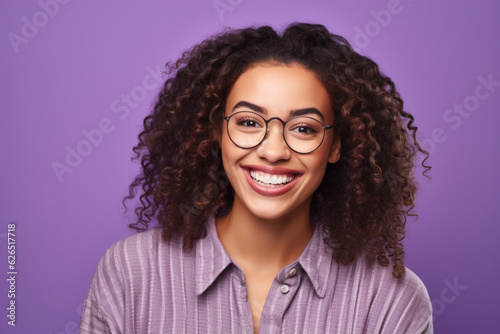 Young cheerful beautiful African American woman student wearing glasses smiling sincerely tilt head to side and look at you dressed in casual style stands on purple plain background