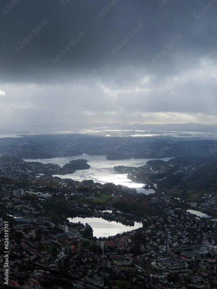 Norwegian landscape of a town with lakes and sunlight beaming through the dark clouds