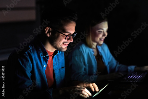 business young friend night couple student laptop computer office businessman businesswoman entertainment tv watching television movie startup evening glowing screen