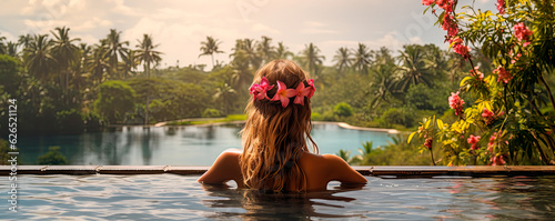 Woman with flowers in hair relaxing in Infinity pool with a view to the jungle. photo