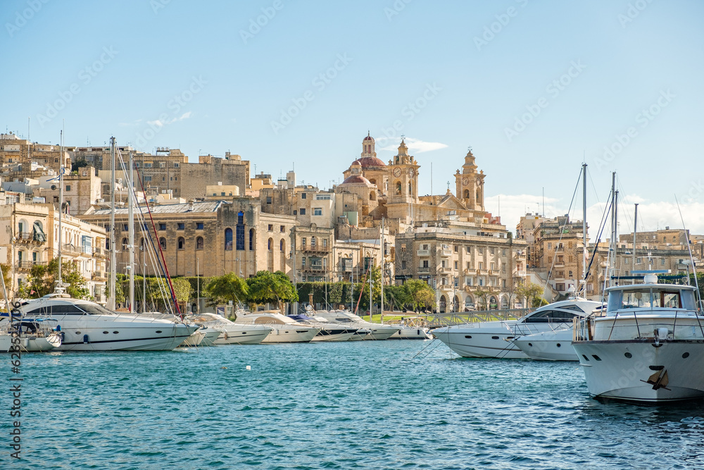 Marina with sailboats and yachts in front of a historical backdrop. The old town of Valletta