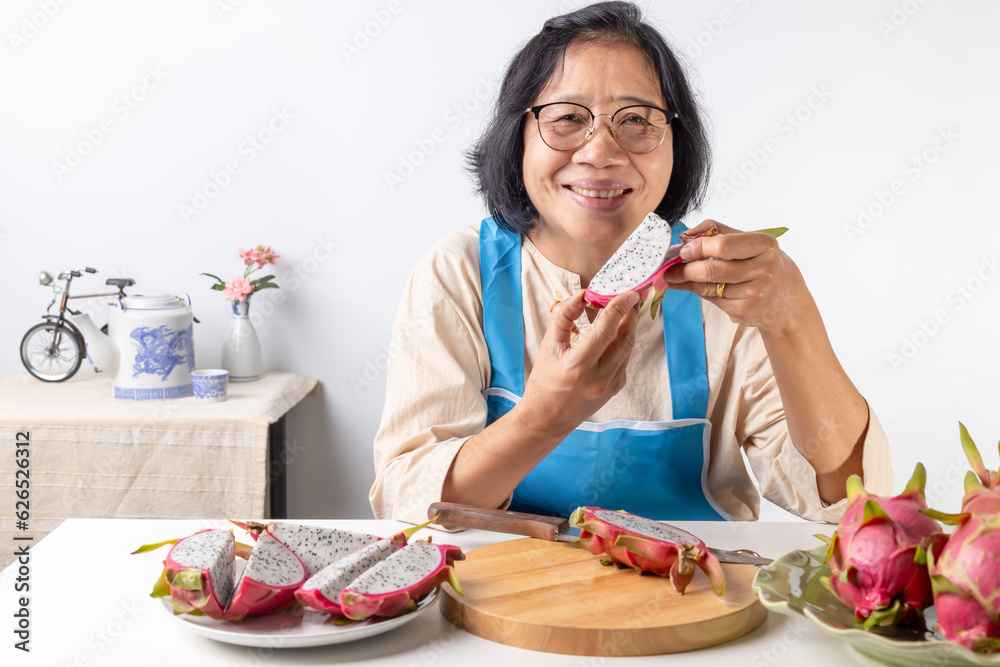 Asian senior woman eating slicing fruit in the kitchen Asian senior woman eating slicing fruit in the kitchen