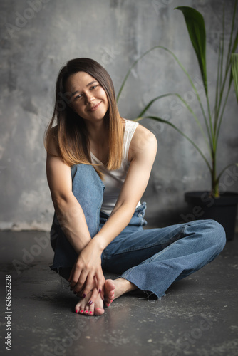 Portrait of a young attractive girl in a white T-shirt and jeans. A girl of oriental appearance in the interior of a stylish apartment. Lifestyle