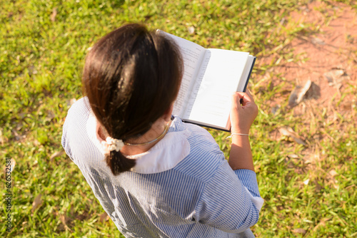 Girl reading a book in the front yard Female student portrait, education concept Happy cute kid smiling with learning.