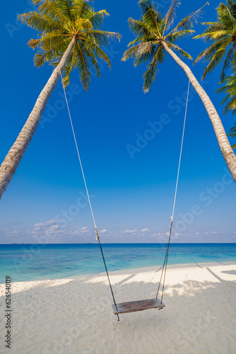 Tropical beach panorama as summer relax landscape with beach swing hanging on palm tree over white sand sea beach banner. Amazing beach vacation summer leisure holiday. Luxury romantic freedom travel