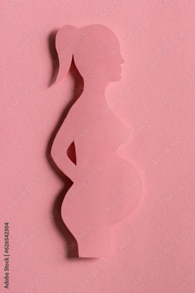 silhouette of pregnant woman on pink background, monochrome. waiting childbirth, reproductology, gynecology. happy duration of pregnancy. concept birth of child. Design cut out of paper. vertical