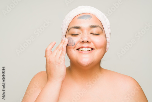 Relaxed plus size woman doing a skin care routine with a mud mask
