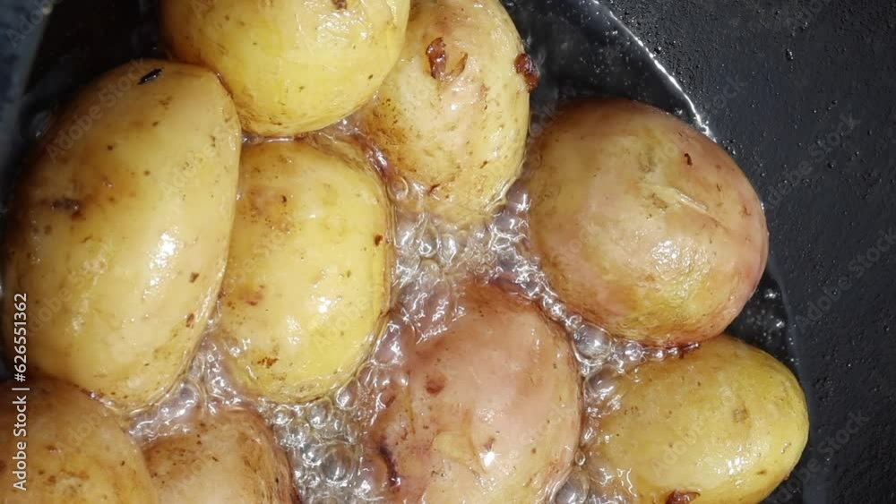 Potatoes are fried in vegetable oil. In a cauldron over an open fire. Close-up. vertical video. Potatoes are fried in vegetable oil. In a cauldron over an open fire. Close-up. vertical video.
