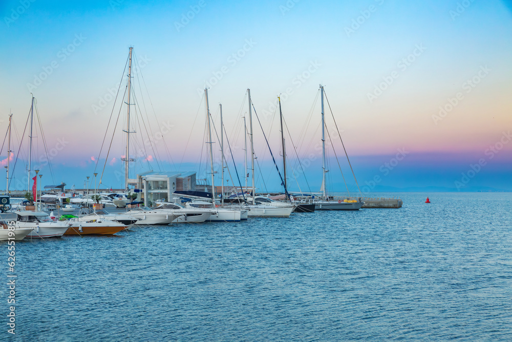 Sailing port at sunrise, jetty, many beautiful well maintained sailing yachts, boats in the seaport, modern water transport, summer holidays, luxury lifestyle and wellness concept