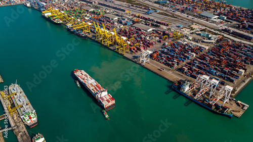 container ship and shipping port loading and unloading cargo from container ship import and export by crane for distributing goods by trailers transported to customers and dealers, aerial  view © SHUTTER DIN