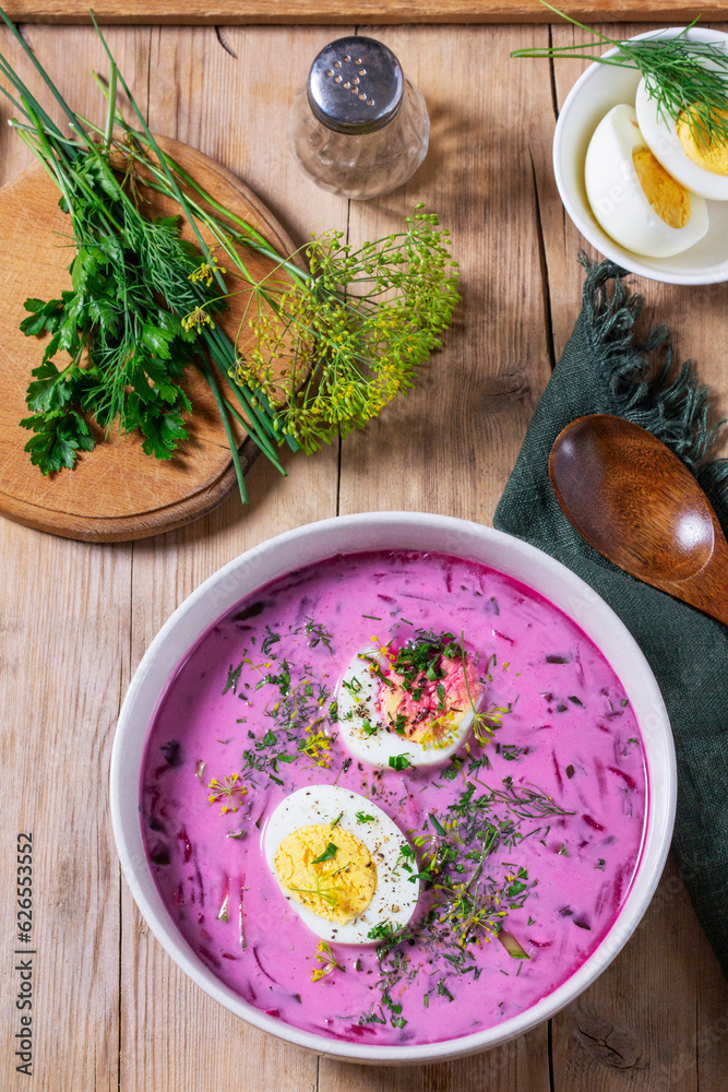 Traditional summer cold beetroot soup with cucumber, egg and sour cream on a wooden background. Rustic style.
