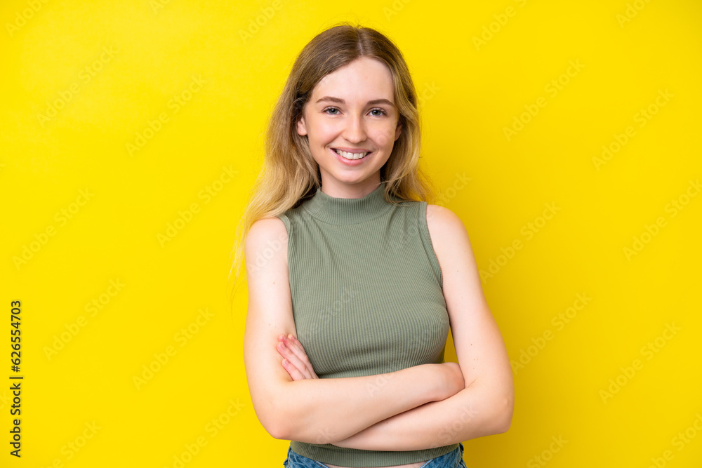 Fototapeta premium Blonde English young girl isolated on yellow background with arms crossed and looking forward