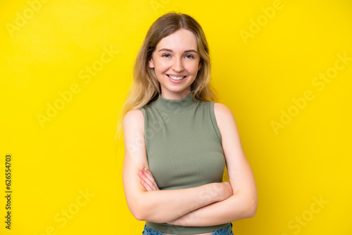 Blonde English young girl isolated on yellow background with arms crossed and looking forward