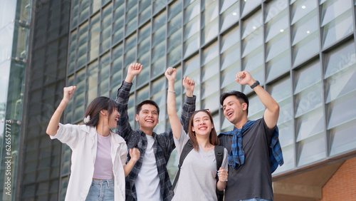Group of happy young entrepreneurs with hands up and laughing to celebrate and excited success for achievements obtained. Undergraduate students celebrate success after end project, teamwork concept