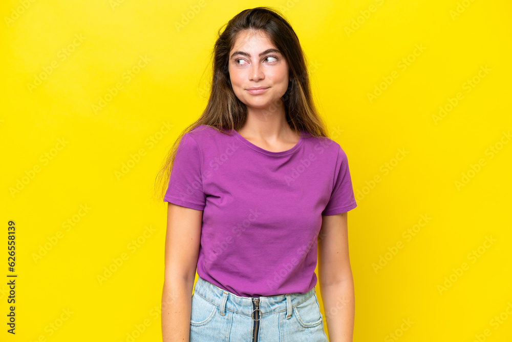 Young caucasian woman isolated on yellow background making doubts gesture looking side Young caucasian woman isolated on yellow background making doubts gesture looking side