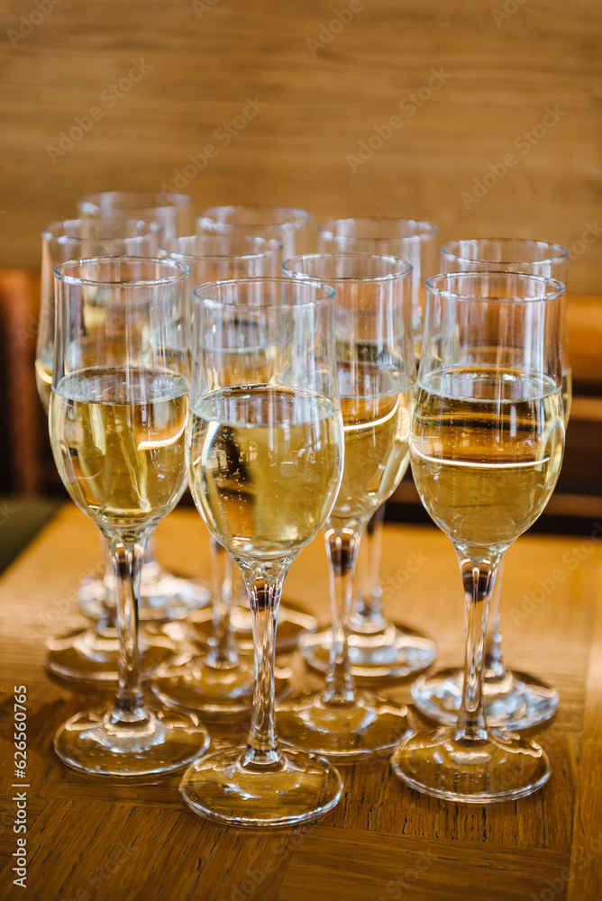 Many glass of white wine. Glasses of champagne on table bar. Buffet. Celebration of birthday, baptism, wedding or corporate party. Catering service. Serves glasses of sparkling wine. Closeup.