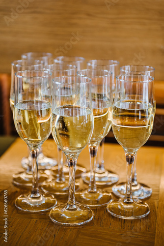 Many glass of white wine. Glasses of champagne on table bar. Buffet. Celebration of birthday, baptism, wedding or corporate party. Catering service. Serves glasses of sparkling wine. Closeup.